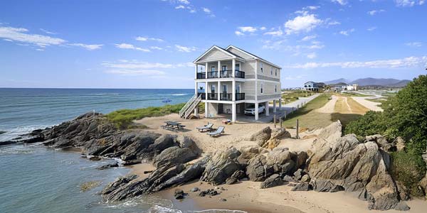 Two-story Topsider home elevated on pilings at a rocky coastal site Two-story Topsider home elevated on pilings at a rocky coastal site