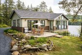 Topsider Home Plan PT-2101 | One-Story Lake House One-story lake home on a wooded lakefront lot with a covered patio and metal roof — Topsider's Patio Collection plan PT-2101, designed for low-maintenance lakeside living.