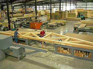 Large roof timber frame trusses are pre-assembled by skilled craftsmen