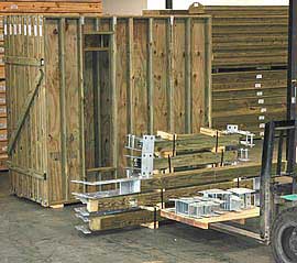 Prepackaged treated lumber walls and structural components with galvanized steel couplings staged and ready for shipment.
